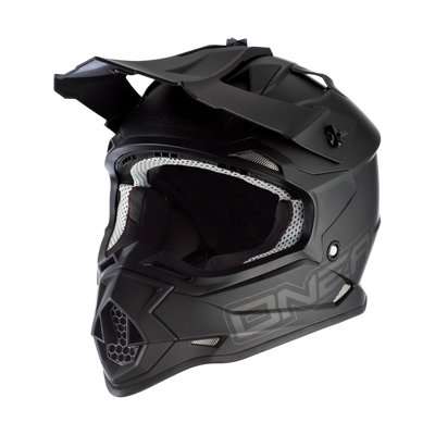 Der O'NEAL 2SRS Helm FLAT ist ein mattschwarzer Fullface-Motocross-Helm mit einem markanten Visier, einem großen Kinnschutz und einer Innenausstattung aus weißem Mesh - ideal für ernsthafte Fahrer. Fotografiert auf einem weißen Hintergrund.
