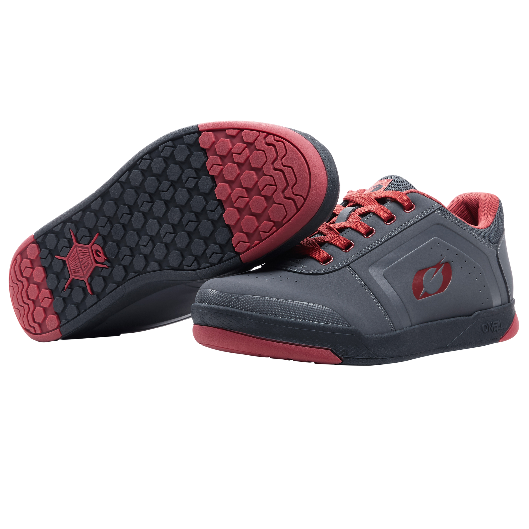 Ein Paar O'NEAL PINNED FLAT Pedal Schuhe in Grau mit roten Sohlen und Schnürsenkeln. Ein Schuh steht aufrecht, während der andere ein schwarzes und rotes Profil aufweist, das bei Fahrten mit flachen Pedalen optimalen Halt bietet. Marke: O'NEAL.