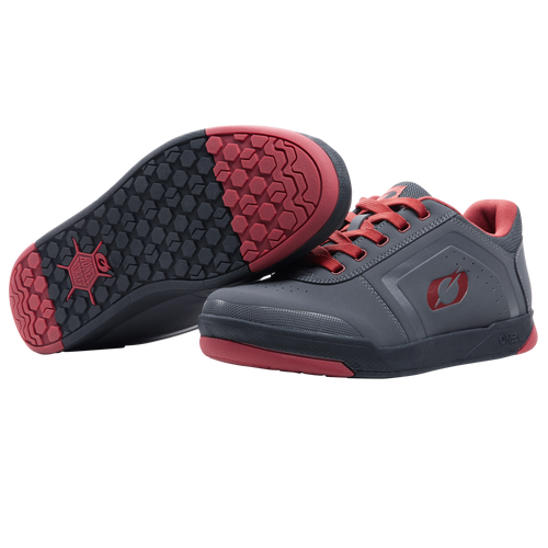 Ein Paar O'NEAL PINNED FLAT Pedal Schuhe in Grau mit roten Sohlen und Schnürsenkeln. Ein Schuh steht aufrecht, während der andere ein schwarzes und rotes Profil aufweist, das bei Fahrten mit flachen Pedalen optimalen Halt bietet. Marke: O'NEAL.