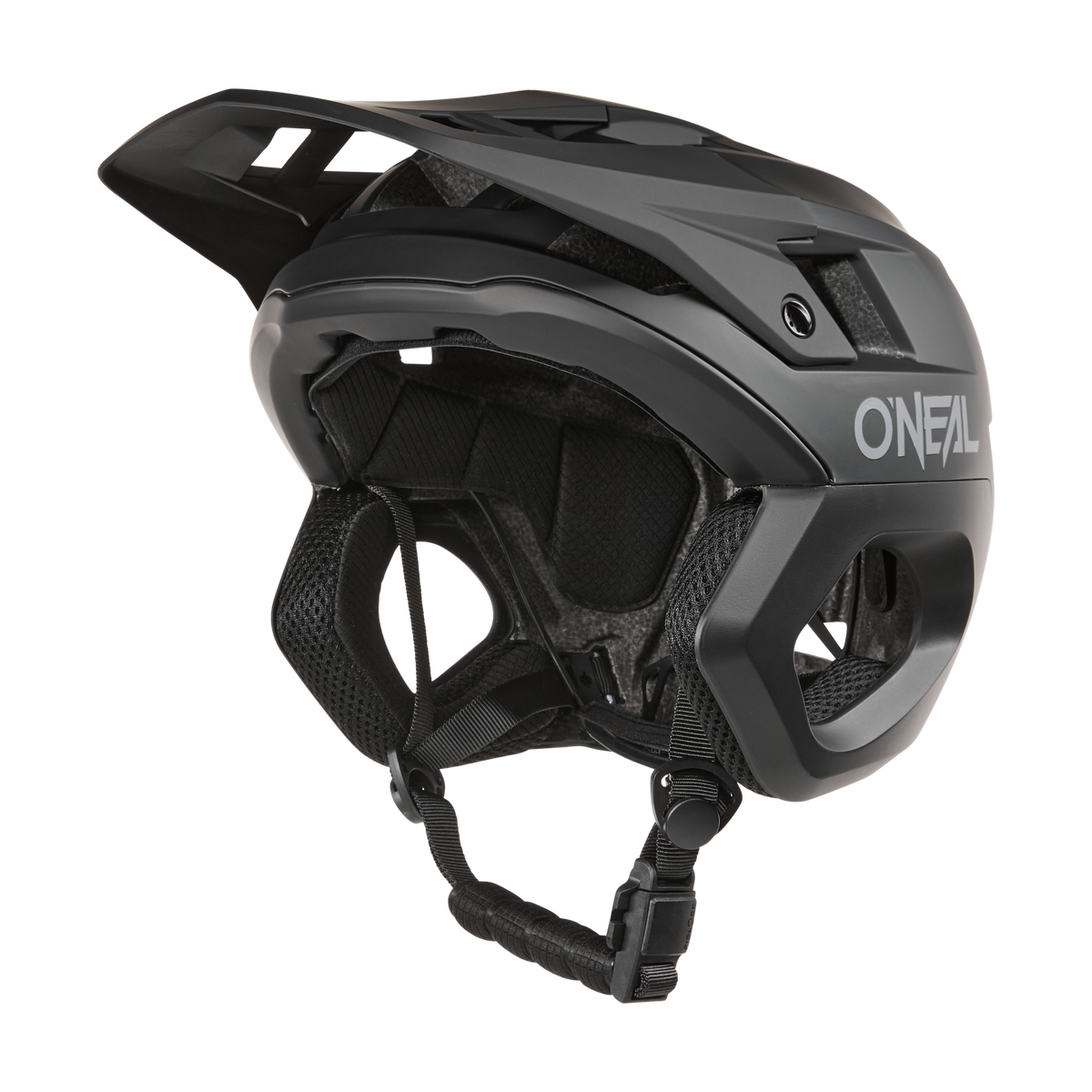 Ein schwarzer O'NEAL TRAPPER Helmet SOLID Mountainbike-Helm mit Visier, seitlichen Belüftungsöffnungen, gepolstertem Innenraum und verstellbarem Kinnriemen wird von der Seite auf einem einfarbigen Hintergrund gezeigt.
