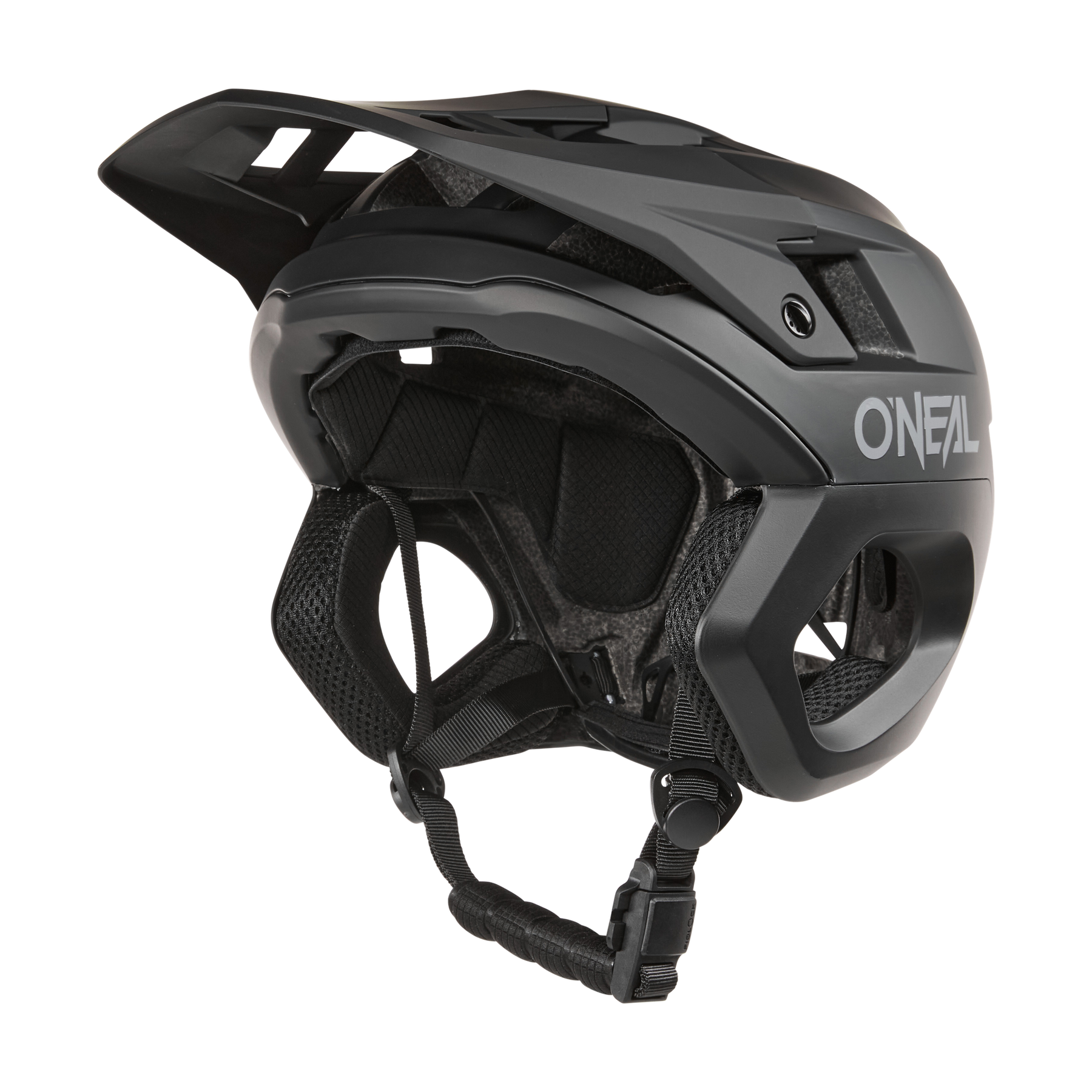Ein schwarzer O'NEAL TRAPPER Helmet SOLID Mountainbike-Helm mit Visier, seitlichen Belüftungsöffnungen, gepolstertem Innenraum und verstellbarem Kinnriemen wird von der Seite auf einem einfarbigen Hintergrund gezeigt.