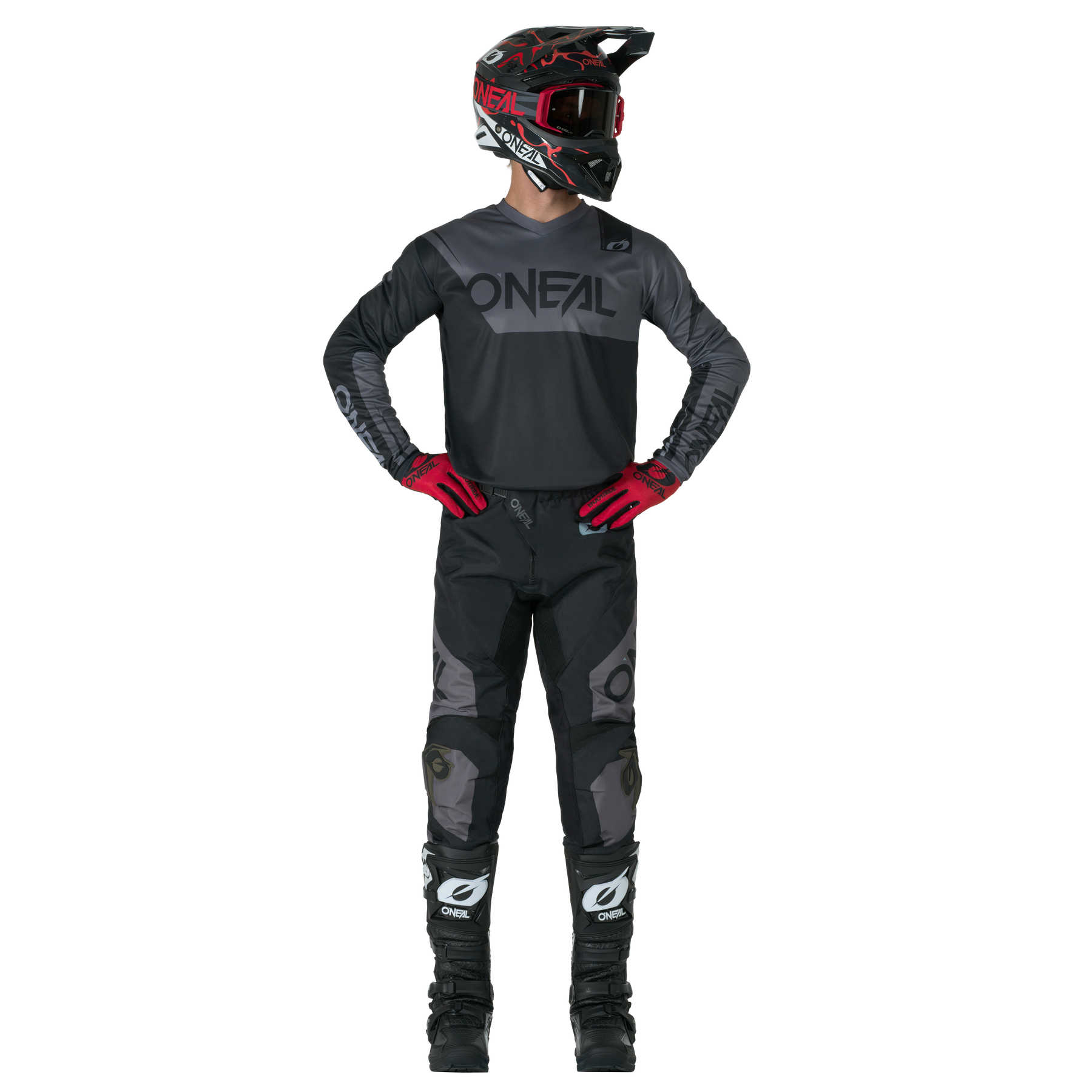 Eine Person in einem kompletten Motocross-Outfit, bestehend aus schwarzer O'NEAL ELEMENT Pants RACEWEAR, einem schwarzen O'NEAL-Helm, Trikot, roten Handschuhen und schwarzen Stiefeln, steht mit den Händen in den Hüften vor einem unifarbenen Hintergrund.