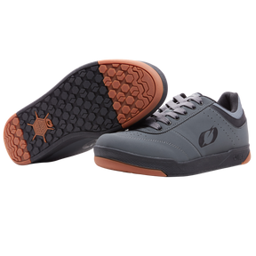 Ein Paar graue O'NEAL PUMPS FLAT Schuhe mit schwarzen Schnürsenkeln und Sohlen mit sechseckigem Profil, braunen Akzenten an der Ferse und der Spitze, einem Logo an der Seite und einem auf der Seite ausgestellten Schuh als Detail. Marke: O'NEAL.