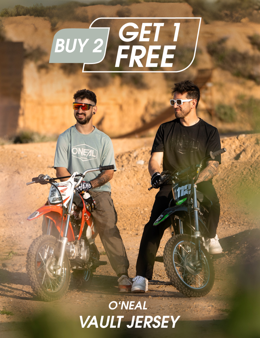 Zwei Männer in O'Neal-Trikots und mit Sonnenbrillen sitzen auf Geländemotorrädern im Freien. Der Text über ihnen lautet "BUY 2 GET 1 FREE". Darunter steht "O'NEAL VAULT JERSEY.