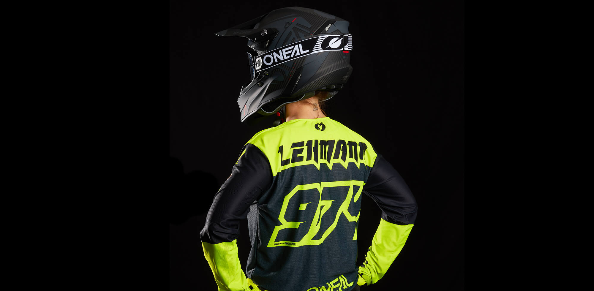 Ein Motocrossfahrer in einem schwarz-neongelben Outfit mit „Lehmann“ und „94“ auf dem Rücken. Der Fahrer trägt einen schwarzen Helm mit dem O'Neal-Logo und scheint mit den Händen in den Hüften vor einem schwarzen Hintergrund zu stehen und von sich weg zu blicken.