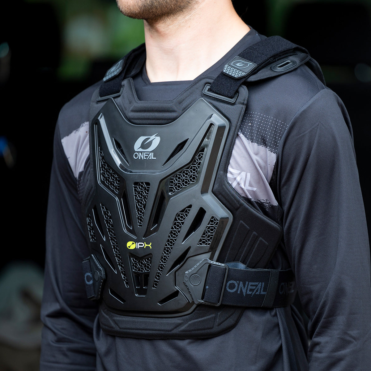 Eine Person trägt einen schwarzen O'Neal-Brustschutz mit verstellbaren Schulter- und Hüftgurten über einem schwarzen Langarmshirt. Der Brustschutz verfügt über belüftete Einsätze und das O'Neal-Logo.