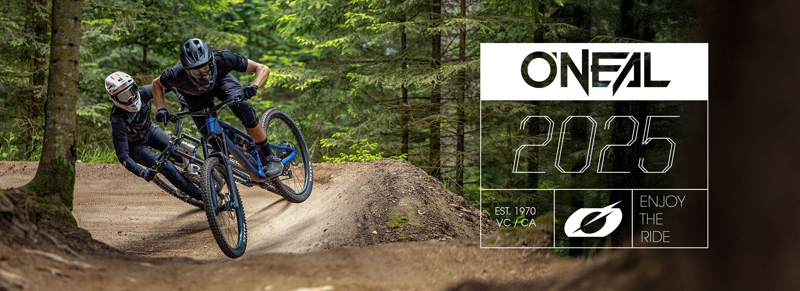 Zwei Radfahrer mit Helmen und Ausrüstung fahren Mountainbikes auf einem Waldweg. Das Bild zeigt das O'NEAL-Logo, „2025“, den Slogan „Enjoy the Ride“ sowie „EST. 1970 NC/CA“.