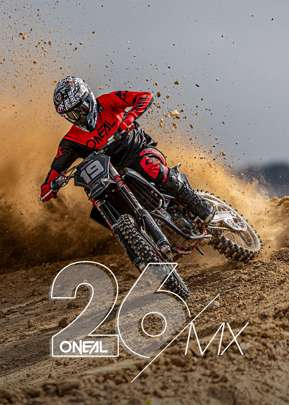 Ein Motocross-Fahrer in roter und schwarzer O'NEAL-Ausrüstung macht eine scharfe Kurve auf einer unbefestigten Strecke und wirbelt dabei Sand auf. Die Nummer 19 ist auf dem Motorrad zu sehen. Der große weiße Text "26 O'NEAL MX" ist am unteren Rand eingeblendet.
