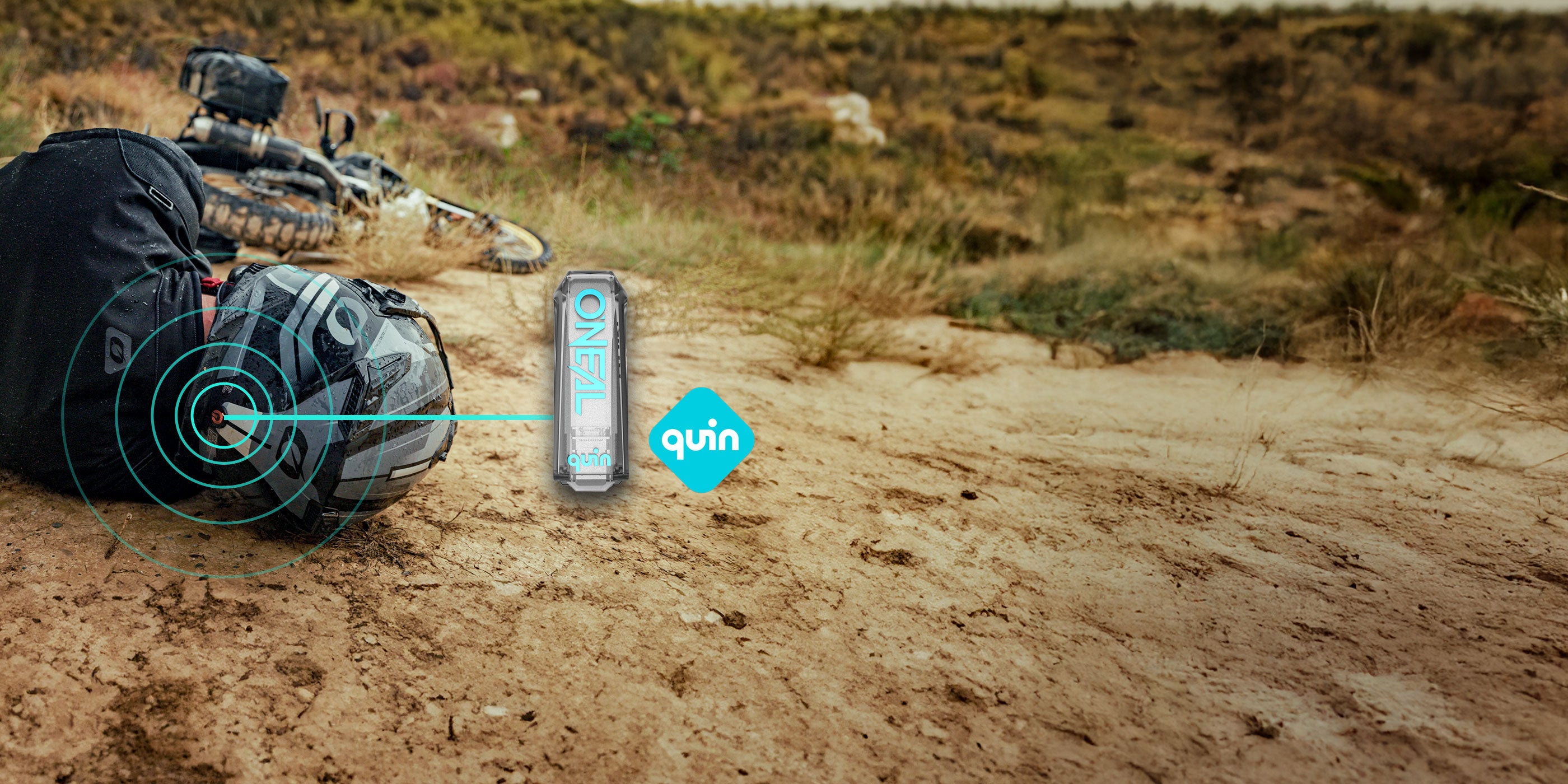 Ein Fahrradhelm und ein Rucksack liegen auf einem Feldweg neben einem Fahrrad. Im Vordergrund sind eine Dose mit der Aufschrift „Oneal“ und dem „Quin“-Logo eingeblendet. Im Hintergrund ist eine trockene, grasbewachsene Landschaft zu sehen.
