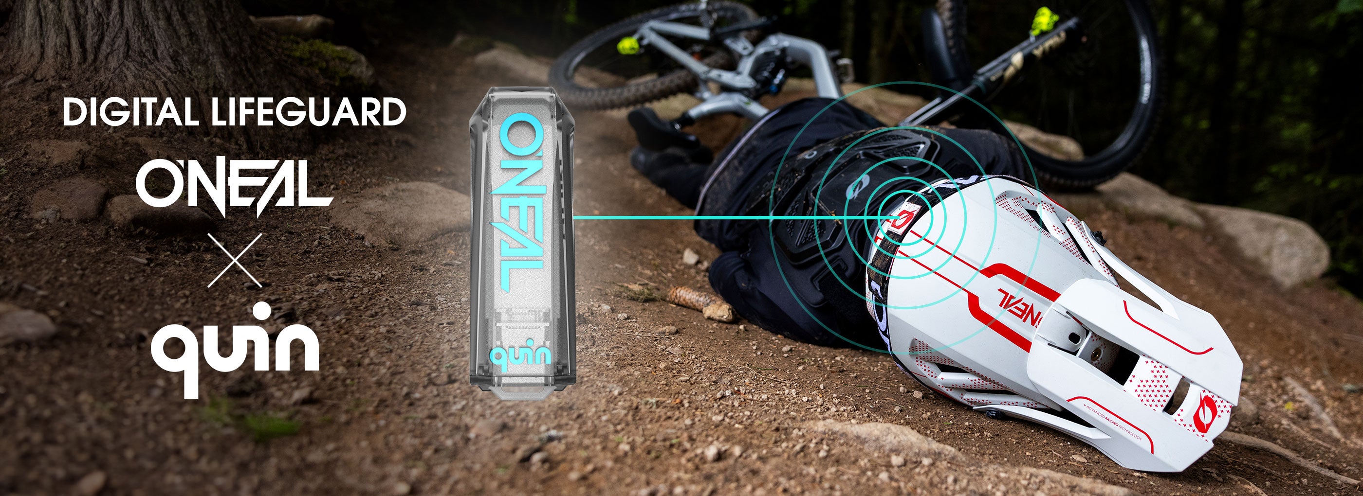 Ein Mountainbiker liegt nach einem Sturz bäuchlings auf einem steinigen Pfad. Er trägt einen weißen O’Neal-Helm mit digitaler Signalgrafik. Der Text lautet „Digital Lifeguard O’Neal x Quin“. Neben dem Fahrer erscheint ein dosenförmiges Gerät.