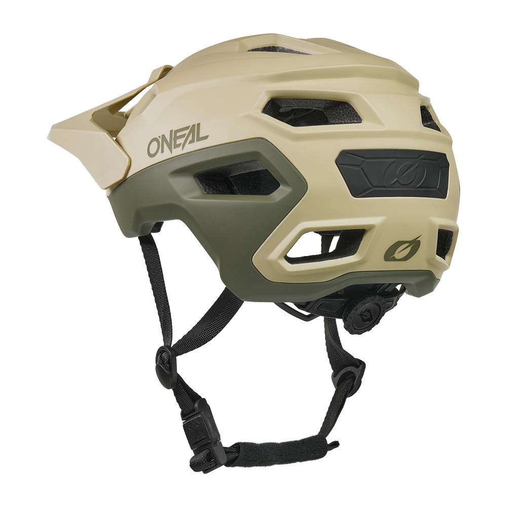 Ein hellbrauner und olivgrüner O'NEAL TRAILFINDER EVO Helm SOLID mit Visier, Belüftungslöchern, verstellbaren schwarzen Kinnriemen und einem hinteren Einstellrad ist auf einem weißen Hintergrund abgebildet.