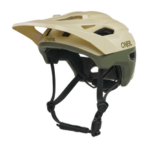 Der O'NEAL TRAILFINDER EVO Helm SOLID ist ein beiger und olivgrüner Mountainbike-Helm mit einem Visier, mehreren Belüftungsöffnungen, verstellbaren schwarzen Kinnriemen und ist mit dem optionalen Quin Smart Safety Sensor kompatibel.
