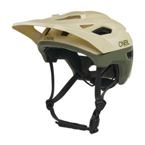 Der O'NEAL TRAILFINDER EVO Helm SOLID ist ein beiger und olivgrüner Mountainbike-Helm mit einem Visier, mehreren Belüftungsöffnungen, verstellbaren schwarzen Kinnriemen und ist mit dem optionalen Quin Smart Safety Sensor kompatibel.