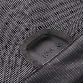 Close-up of the O'NEAL JUNCTION Protective Backpack from O'NEAL Europe with black polka dot mesh, thin striped fabric and a small reinforced opening. A partially readable label with text and symbols is also visible.