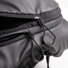 Close-up of the O'NEAL JUNCTION Protective Backpack from O'NEAL Europe with two partially opened zips with black cord loops and plastic handles that highlight the robust material and detailed stitching.