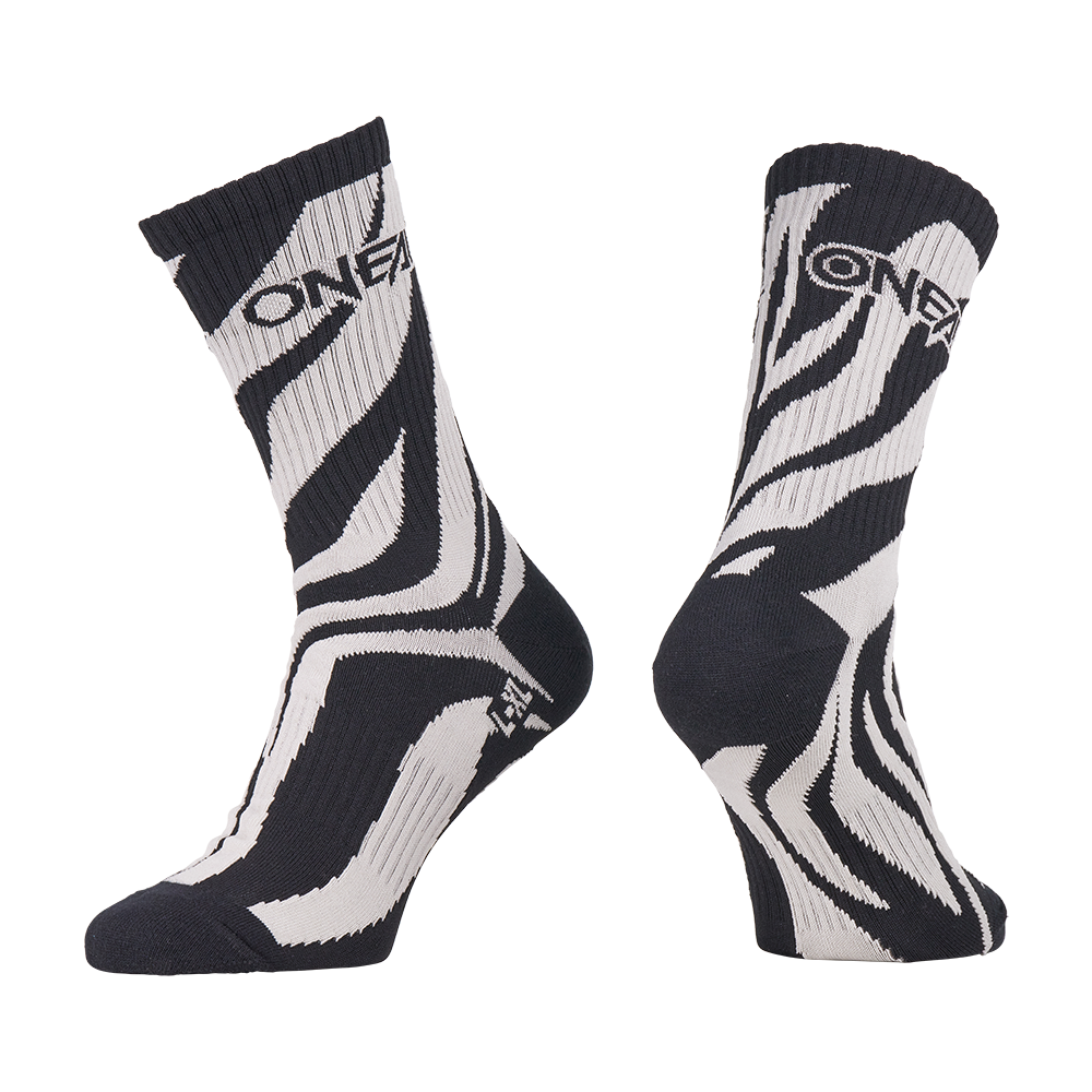 Die O'NEAL MTB Performance Socke WILD ist ein Paar schwarz-weiße Socken mit einem auffälligen Zebrastreifen-Design und dem "O'NEAL"-Schriftzug am oberen Ende. Eine Socke ist von vorne abgebildet, die andere von der Seite.