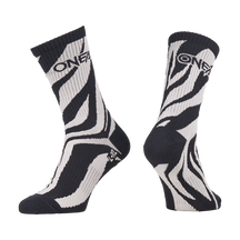 Die O'NEAL MTB Performance Socke WILD ist ein Paar schwarz-weiße Socken mit einem auffälligen Zebrastreifen-Design und dem "O'NEAL"-Schriftzug am oberen Ende. Eine Socke ist von vorne abgebildet, die andere von der Seite.