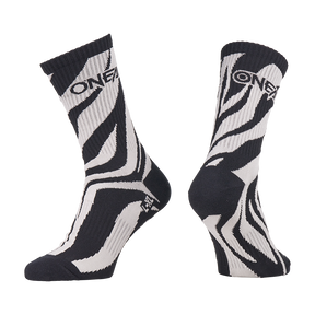 Die O'NEAL MTB Performance Socke WILD ist ein Paar schwarz-weiße Socken mit einem auffälligen Zebrastreifen-Design und dem "O'NEAL"-Schriftzug am oberen Ende. Eine Socke ist von vorne abgebildet, die andere von der Seite.