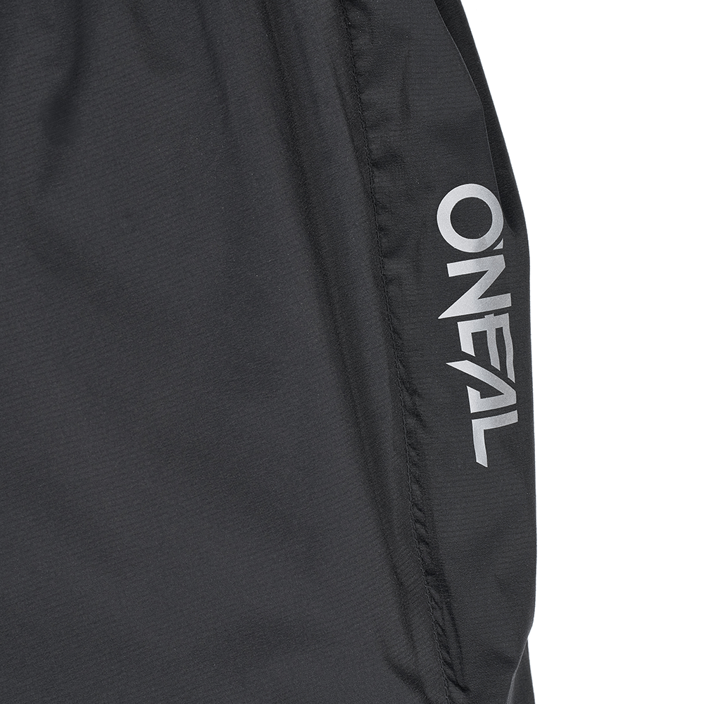 Nahaufnahme einer schwarzen O'NEAL TORRENT Regenhose mit dem weißen "O'NEAL"-Logo entlang einer Naht. Entworfen für Sport und Outdoor.