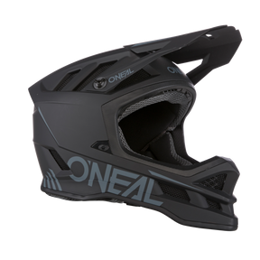 Dieser O'NEAL BLADE Polyacrylite Helm SOLID ist ein mattschwarzer Integralhelm für Mountainbikes mit großen Belüftungsöffnungen, einem verstellbaren Visier und einem Kinnschutz. Der Markenname „O'NEAL“ erscheint in hellblauer Schrift auf der Seite. Er wird vor einem schlichten schwarzen Hintergrund angezeigt.