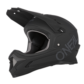 Der O'NEAL SONUS Helm SOLID ist ein mattschwarzer Fullface-MTB-Helm mit Visier und Kinnschutz, mit großem O'NEAL-Branding an der Seite und grau-schwarzer Innenpolsterung.