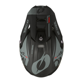 Draufsicht des grau-schwarzen Offroad-Motorradhelms O'NEAL 10SRS Carbon Helm PRODIGY mit elegantem aerodynamischem Design. Dieser leichte Helm mit verschiedenen Logos, darunter „O'NEAL“, an den Seiten verfügt über ein zentrales Belüftungssystem. Die Außenseite aus Kohlefaser ist mit stilisierten Grafiken verziert.