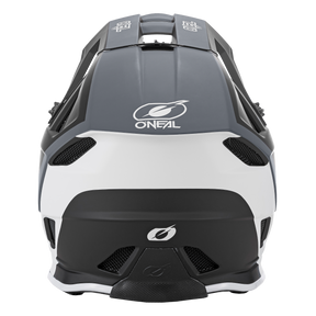 Eine Rückansicht des O'NEAL BLADE Hyperlite Helm CHARGER Motocross-Helms in Schwarz und Weiß. Der Helm zeigt den Markennamen „O'NEAL“ und sein unverwechselbares stilisiertes „O“-Logo. Er ist mit Belüftungsöffnungen ausgestattet und verfügt über eine schlanke, aerodynamische Form und besteht aus strapazierfähigem Fiberglas.