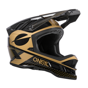 Ein O'NEAL BLADE Polyacrylite Helm ACE in Schwarz und Gold, mit Integraldesign und eckigem Visier. Der Helm ist mit einem schwarzen runden Emblem und dem Wort „O'NEAL“ in weißen Großbuchstaben verziert. Sein Design umfasst ein geometrisches Muster sowie schlanke, aerodynamische Linien und ist damit perfekt für MTB-Enthusiasten.