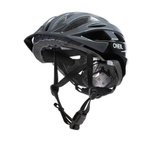 Der O'NEAL OUTCAST Helm SPLIT von O'NEAL, abgebildet in Schwarz/Grau, verfügt über Belüftungsschlitze, eine gepolsterte Polsterung und verstellbare Kinnriemen auf weißem Hintergrund. Dieser Inmold-MTB-Helm bietet höchsten Komfort und Schutz bei jeder Fahrt.
