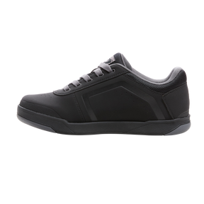 Eine Seitenansicht des O'NEAL PINNED FLAT Pedalschuhs in Schwarz mit grauen Schnürsenkeln und grauer Sohle. Der Schuh hat ein schlankes Design mit minimalen Details und einem gepolsterten Knöchelkragen und bietet hervorragenden Tragekomfort und ein modernes, funktionales Erscheinungsbild, das sich sowohl zum Radfahren als auch für die Freizeit perfekt eignet.