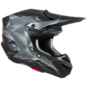 Ein O'NEAL 5SRS Polyacrylite Helm SURGE in mattem Schwarz und Grau, verziert mit eckigen, geometrischen Designs. Dieser hochwertige technische Helm verfügt über ein markantes Visier und einen Kinnschutz mit dem Markennamen „ONEAL“ in fetten weißen Buchstaben an der Seite. Das Innere verfügt über ein gepolstertes Futter für ultimativen Komfort und Sicherheit.