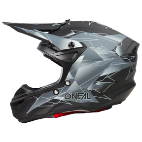 Ein eleganter schwarz-grauer O'NEAL 5SRS Polyacrylite Helm SURGE, verziert mit eckigen, geometrischen Designs. Der Helm trägt stolz „ONEAL“ auf der Seite und verfügt über ein ausgeprägtes Visier, Belüftungsschlitze und einen Kinnschutz. Sein modernes Design verkörpert hohe Leistung und Sicherheit und spiegelt erstklassige Ingenieursqualität wider.