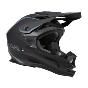 Der O'NEAL DROP DH Helm SOLID ist ein schwarz-grauer Integralhelm für Motocross mit Visier, aerodynamischem Design und mehreren Belüftungsöffnungen. Der Markenname „O'NEAL“ ist deutlich sichtbar an der Seite angebracht. Dieser Helm kombiniert Sicherheit und Komfort mit seiner gepolsterten Innenausstattung für verbesserten Schutz.
