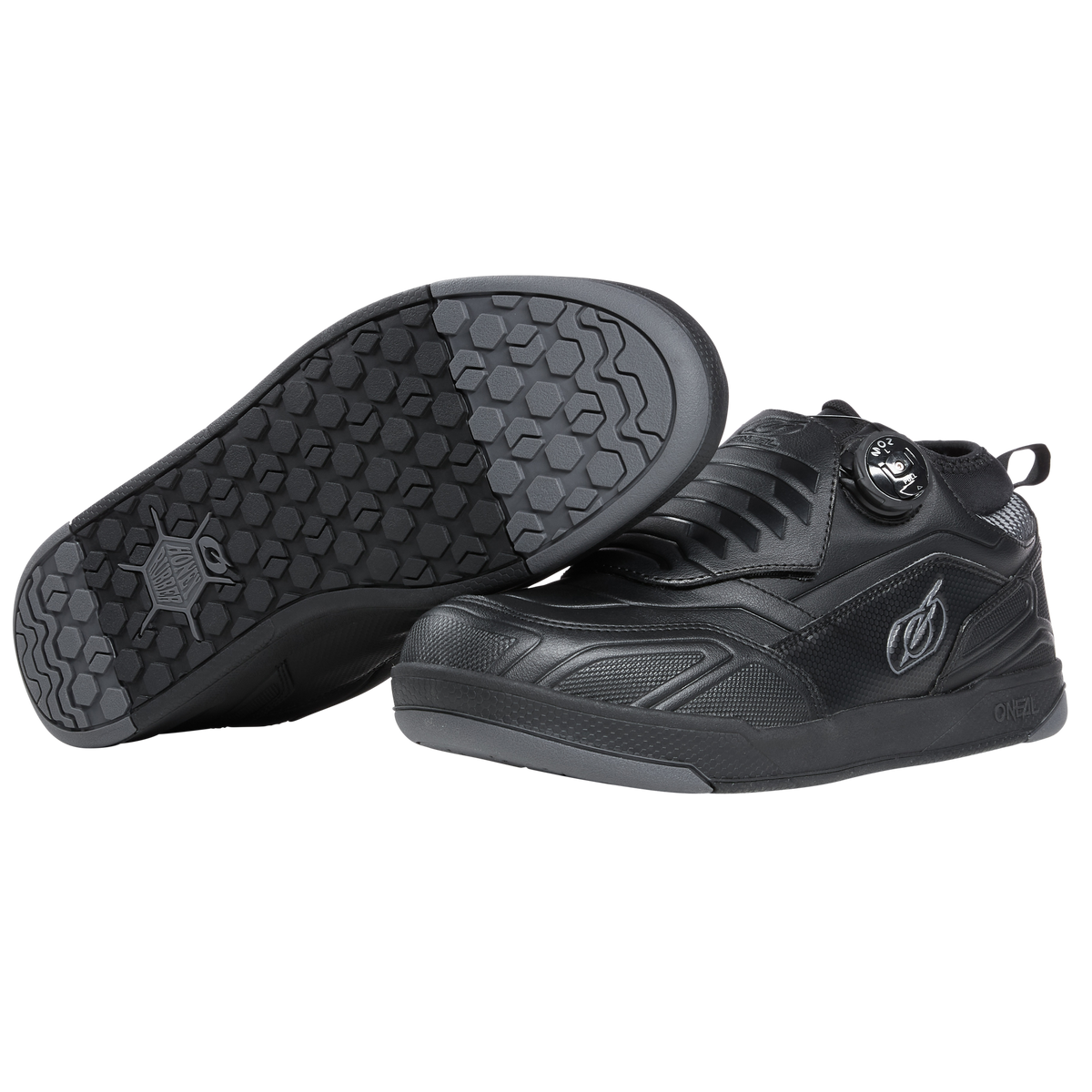 Ein Paar O'NEAL LOAM WP FLAT Schuhe in Schwarz mit sechseckigem Profilmuster auf der Sohle. Ein Schuh liegt auf der Seite und zeigt die Unterseite der Sohle, während der andere aufrecht steht. Die Schuhe sind mit einem O'NEAL-Logo versehen und verfügen über einen Drehmechanismus zum Anpassen der Passform.