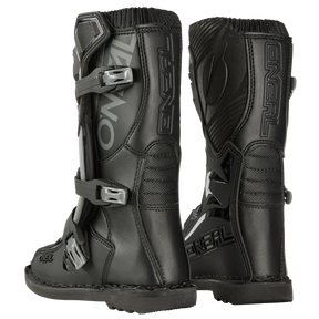 Ein Paar schwarze O'NEAL TRIBUTE Stiefel Kinder mit silbernen Schnallen und auffälligem Branding an den Seiten. Die Stiefel bieten sowohl Komfort als auch Sicherheit und haben verstärkte Sohlen und Fersenschützer, die für das Offroad-Motorradfahren konzipiert sind. Das Bild zeigt die Stiefel von der Seite und von hinten, was ihr robustes Design hervorhebt.