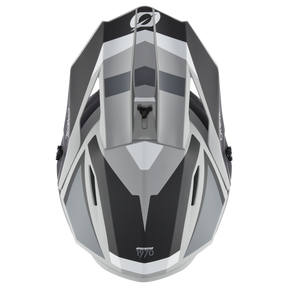 Eine Draufsicht auf den modernen, aerodynamischen O'NEAL 1SRS Helm STREAM in Schwarz und Grau mit eckigen Linien und schlankem Design. Die hochwertige Verarbeitung wird durch die Belüftungsöffnungen und das markante Grafikdesign mit der Zahl „1970“ unten in der Mitte deutlich.