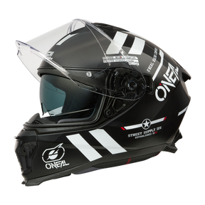 Der O'NEAL CHALLENGER Helm WARHAWK ist ein schwarzer Motorradhelm mit weißen Streifen, Logos und Text. Er besteht aus robustem ABS und verfügt über ein klares Visier und Branding. Sein aerodynamisches Design wird durch Belüftungsschlitze und grafische Details für einen markanten Look verstärkt.