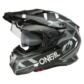 Der O'NEAL D-SRS Helm SQUARE ist ein schwarz-grauer Motorradhelm mit geometrischen Mustern und dem „O’NEAL“-Logo an der Seite. Dieser Helm verfügt über ein klares Visier, einen integrierten Sonnenschutz, ein aerodynamisches Design und mehrere Belüftungsöffnungen und bietet einen modernen und sportlichen Look.