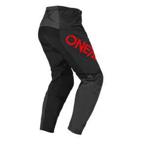 Eine schwarz-graue O'NEAL ELEMENT Hose RACEWEAR mit dem Wort „ONEAL“ in großen roten Buchstaben auf dem rechten Oberschenkel. Diese Hose wurde für Motorsportbegeisterte entworfen und bietet verstärkte Knie für Haltbarkeit und Komfort (Komfort und Schutz) beim Fahren im Gelände.