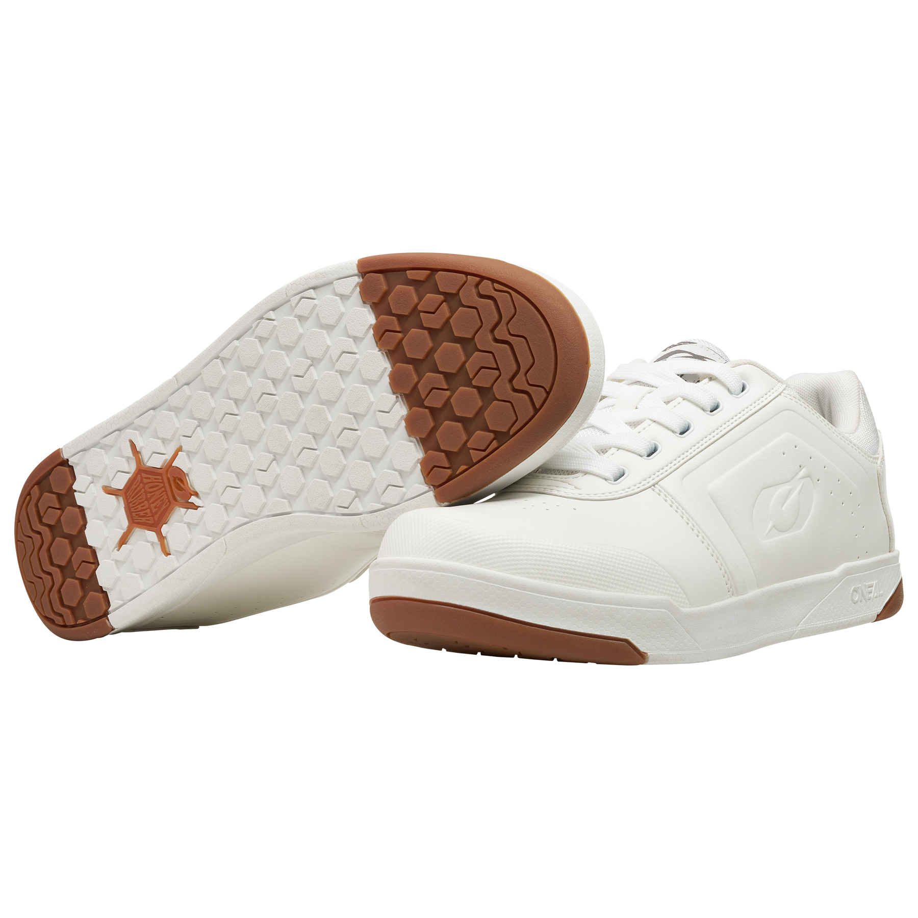 Der O'NEAL PINNED FLAT Pedal Schuh in Weiß wird auf weißem Hintergrund präsentiert. Ein Schuh liegt auf der Seite und präsentiert eine Sohle mit sechseckigem Muster und braunen Akzenten für hervorragenden Halt, während der andere aufrecht steht und sein schlankes Design und die Schnürsenkel hervorhebt.