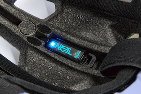 Nahaufnahme des Quin Smart Safety Sensors der Marke O'NEAL mit leuchtend blauem Licht und der Aufschrift „Quinn“, nahtlos integriert in die Polsterung des O'NEAL TRAILFINDER EVO Solid Quin Bundle-Helms – perfekt für jedes Abenteuer.