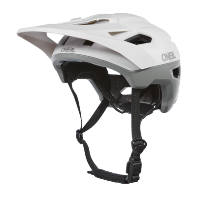 Der O'NEAL TRAILFINDER EVO Helm SOLID in Weiß/Grau verfügt über ein Visier, verstellbare schwarze Riemen und Belüftungsschlitze. Ideal für Trailriding-Enthusiasten. Sein schlankes Design ist mit dem Quin Smart Safety Sensor für verbesserten Schutz kompatibel.
