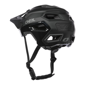 Der O'NEAL TRAILFINDER EVO Helm SOLID in Schwarz verfügt über eckige Belüftungsöffnungen, einen verstellbaren Kinnriemen und ein kleines hinteres Visier auf weißem Hintergrund.