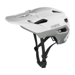 Das O’NEAL TRAILFINDER EVO Solid Quin Bundle ist ein weiß-grauer Fahrradhelm mit Visier, Belüftungslöchern, Inmold-Technologie und verstellbaren schwarzen Riemen, abgebildet vor weißem Hintergrund.
