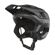 Der O'NEAL TRAPPER Helm SOLID in Schwarz verfügt über ein Visier, einen verstellbaren Kinnriemen, eine Belüftung für die Luftzirkulation und den Fidlock® Magnetverschluss für sicheren und bequemen Schutz und verkörpert ein schlankes Design, das ideal zum Radfahren ist.