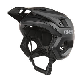 Der O'NEAL TRAPPER Helm SOLID in Schwarz verfügt über ein Visier, einen verstellbaren Kinnriemen, eine Belüftung für die Luftzirkulation und den Fidlock® Magnetverschluss für sicheren und bequemen Schutz und verkörpert ein schlankes Design, das ideal zum Radfahren ist.