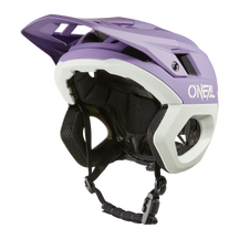Der O'NEAL TRAPPER Helmet SOLID ist ein eleganter und aerodynamischer Mountainbike-Helm in Lila/Hellgrau mit großem Visier und schwarzen, verstellbaren Riemen. Er trägt das „ONEAL“-Logo und verfügt über einen Fidlock® Magnetverschluss für sicheren Halt – ideal für Enduro-Fahrer.