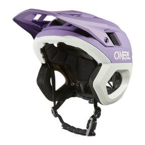 Der O'NEAL TRAPPER Helmet SOLID ist ein eleganter und aerodynamischer Mountainbike-Helm in Lila/Hellgrau mit großem Visier und schwarzen, verstellbaren Riemen. Er trägt das „ONEAL“-Logo und verfügt über einen Fidlock® Magnetverschluss für sicheren Halt – ideal für Enduro-Fahrer.