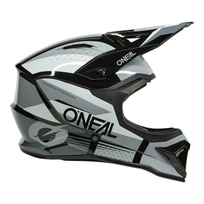 Der O'NEAL 1SRS Helmet RC ist ein schwarzer, weißer und grauer Motocross-Helm mit Visier, auffälligen grafischen Motiven an der Seite und dem Markennamen O'NEAL.