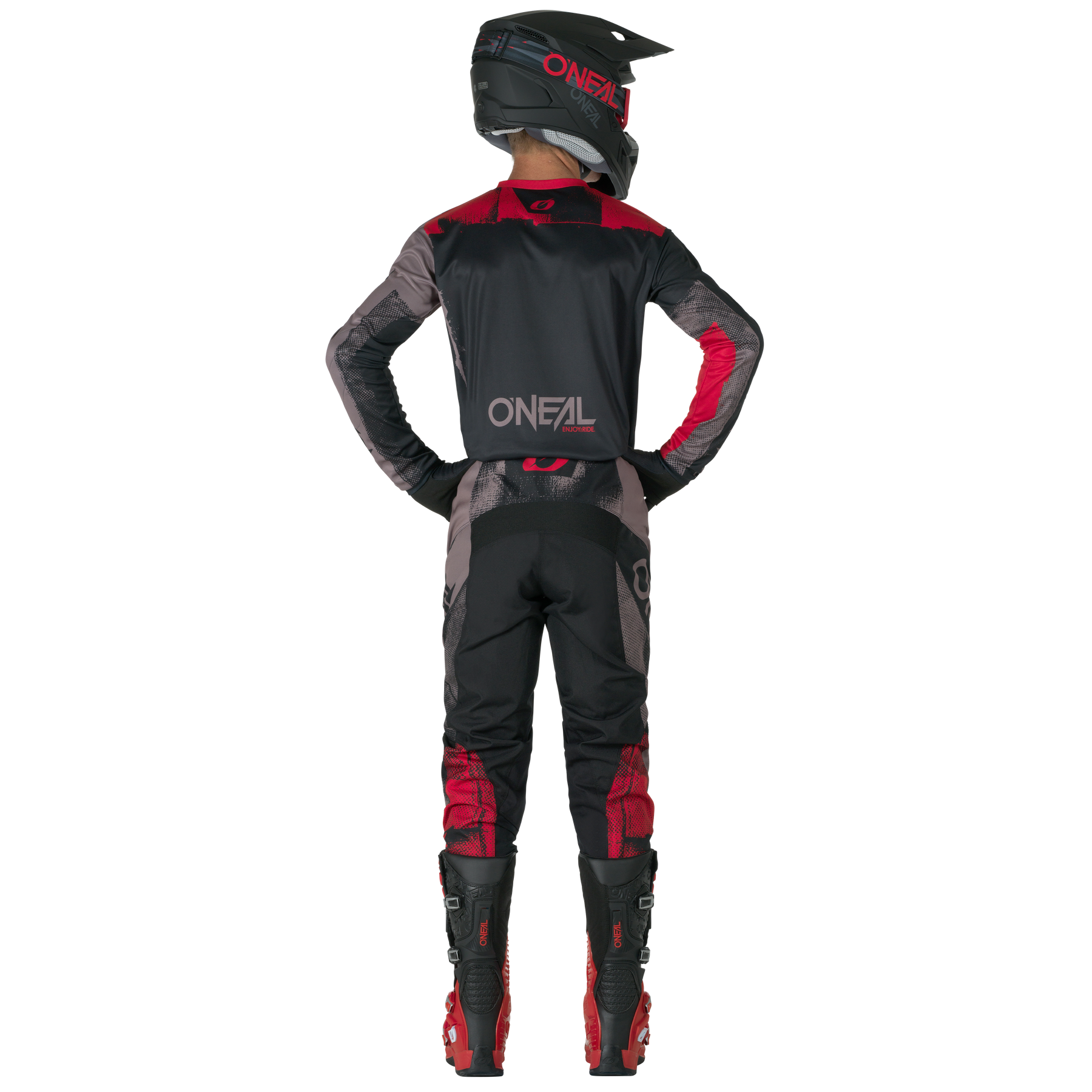 Eine Person in schwarzer und roter O'NEAL ELEMENT Pants ROLLER Motocross-Ausrüstung, Helm und Stiefeln steht mit den Händen in den Hüften von der Kamera abgewandt. Auf der Rückseite des Outfits ist das "O'NEAL"-Logo zu sehen.